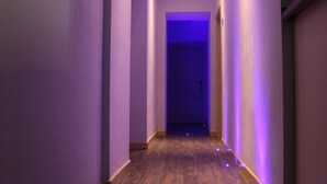 A narrow hallway with purple lighting, wooden flooring, and a door at the end. - Dolce Vita Rooms & Breakfast (Naples)