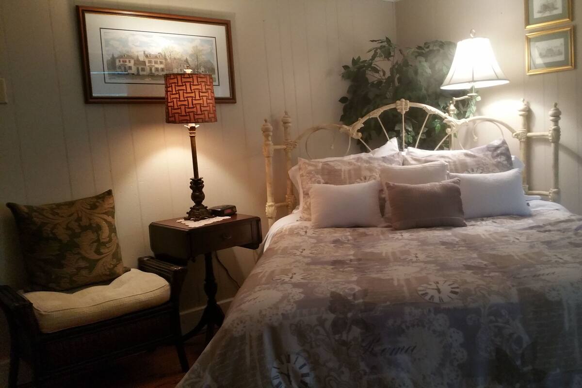 A bedroom with a bed, a nightstand, a chair, and a lamp.