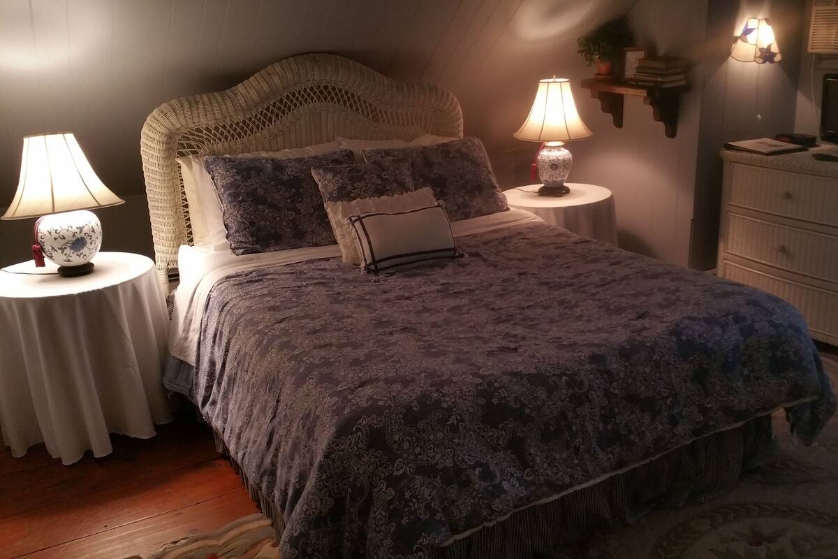 A neatly arranged bedroom with a large bed, two bedside tables with lamps, a television, and a dresser.