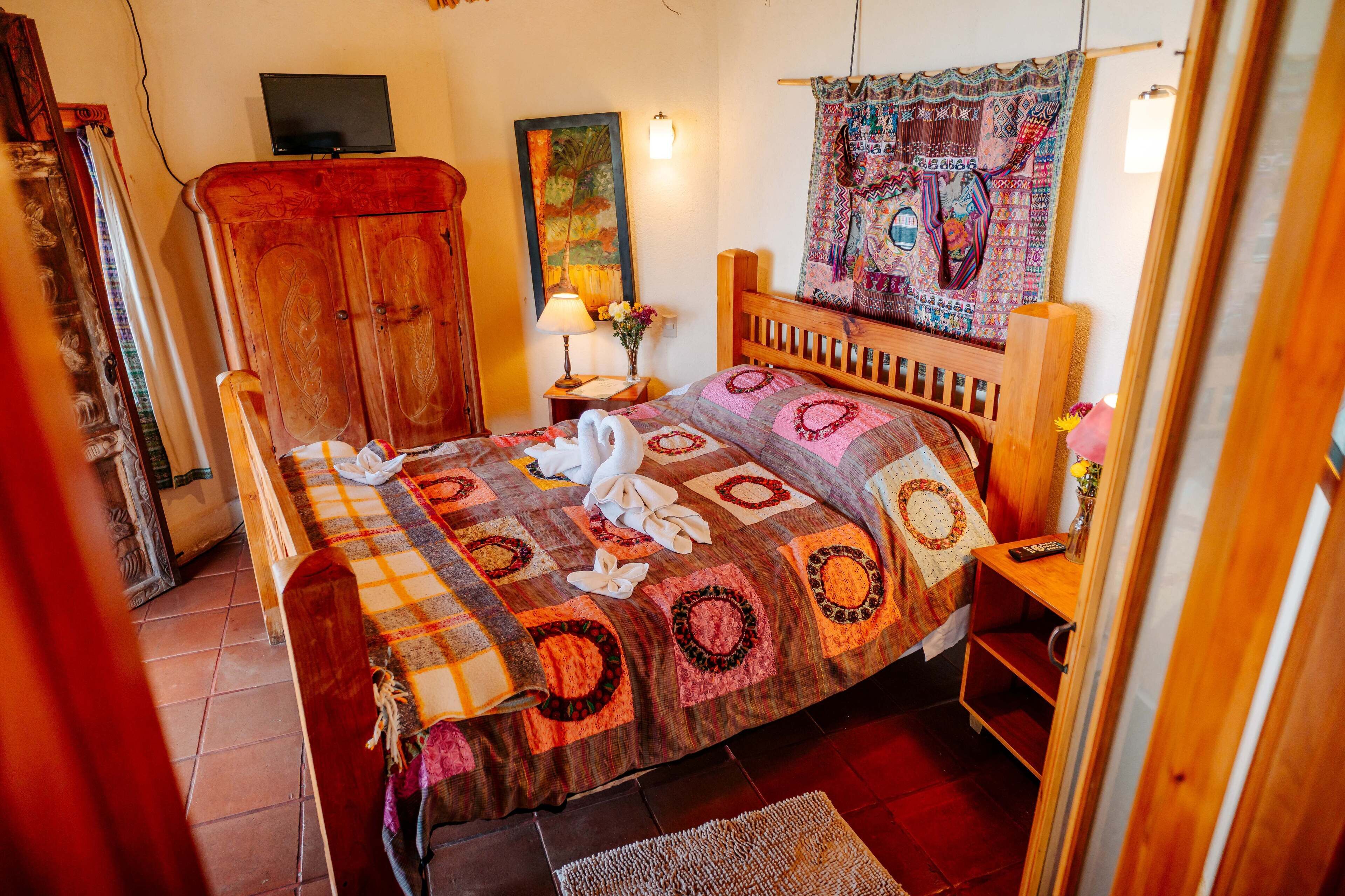 Un dormitorio con cama, armario de madera, televisión y un tapiz.