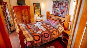 Un dormitorio con cama, armario de madera, televisión y un tapiz.