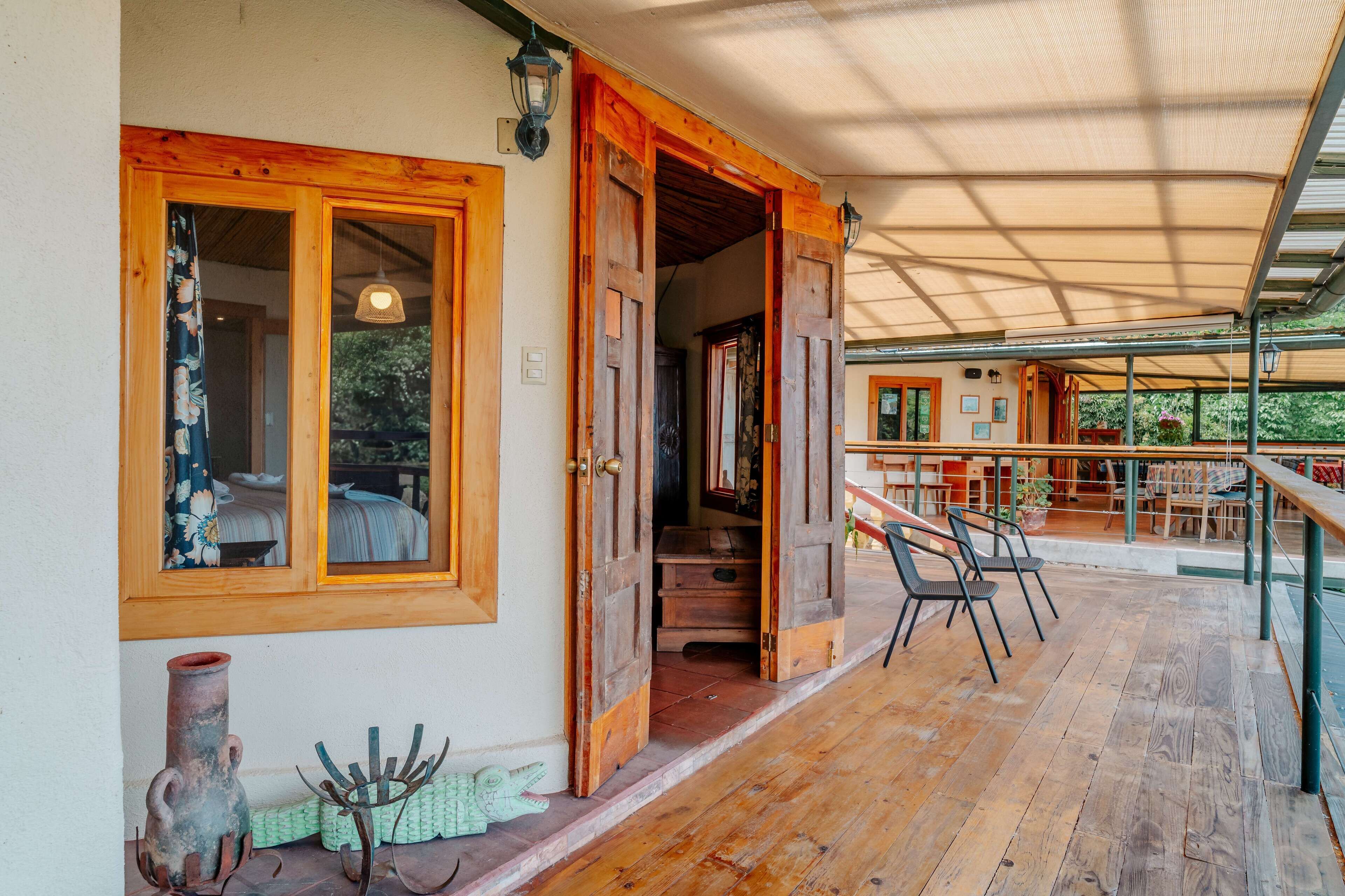 A wooden porch with a covered seating area, a staircase leading to an upper level, and a rustic exterior with wooden doors and windows.