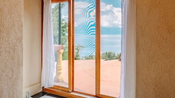 Un baño con bañera, ventana con vista a la playa y techo de madera.
