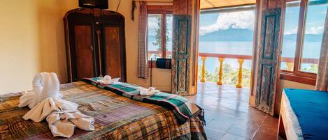 Una habitación con cama, armario, televisión y balcón con vista al mar.