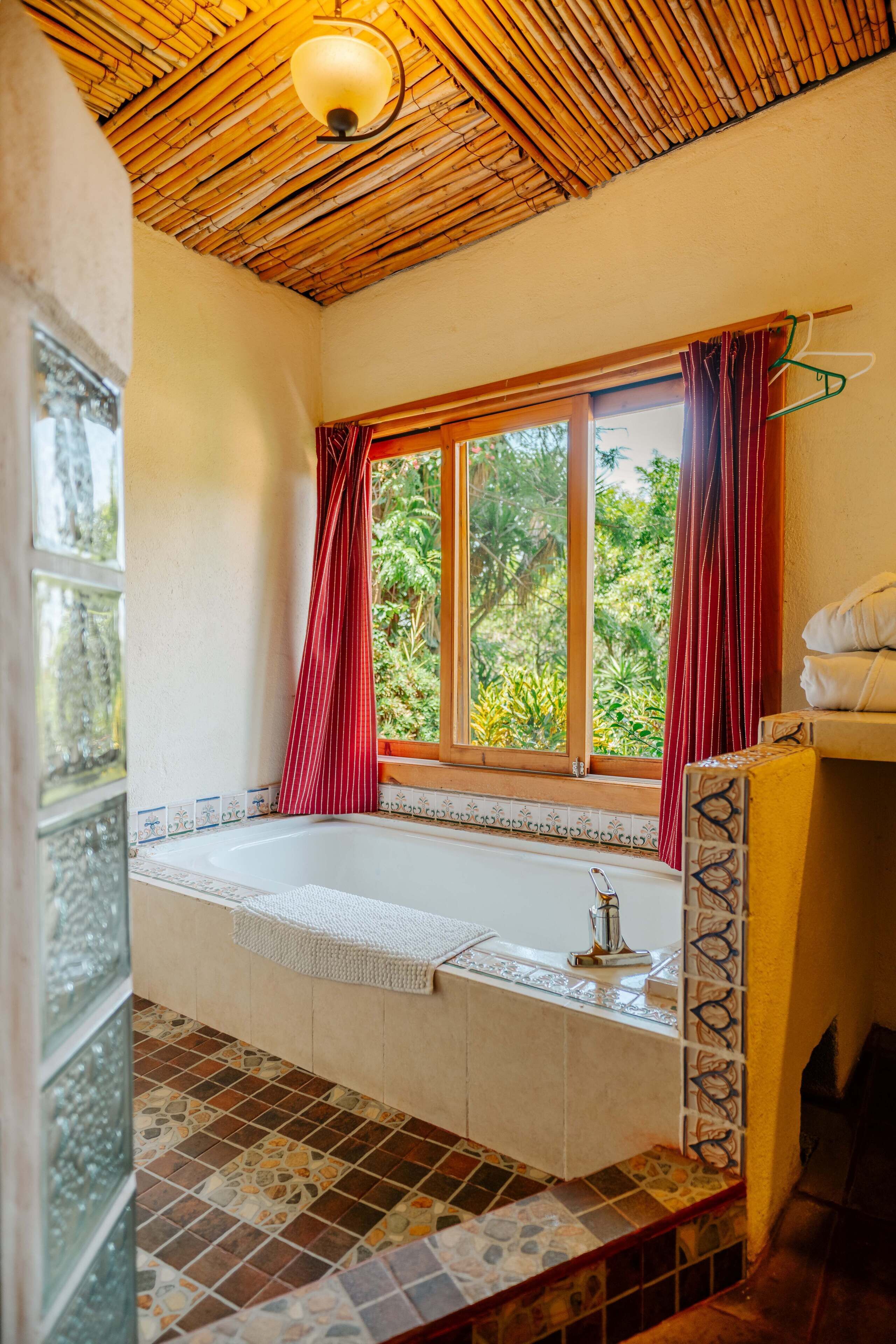 Ein Badezimmer mit großem Fenster, einer Badewanne und gefliestem Boden.