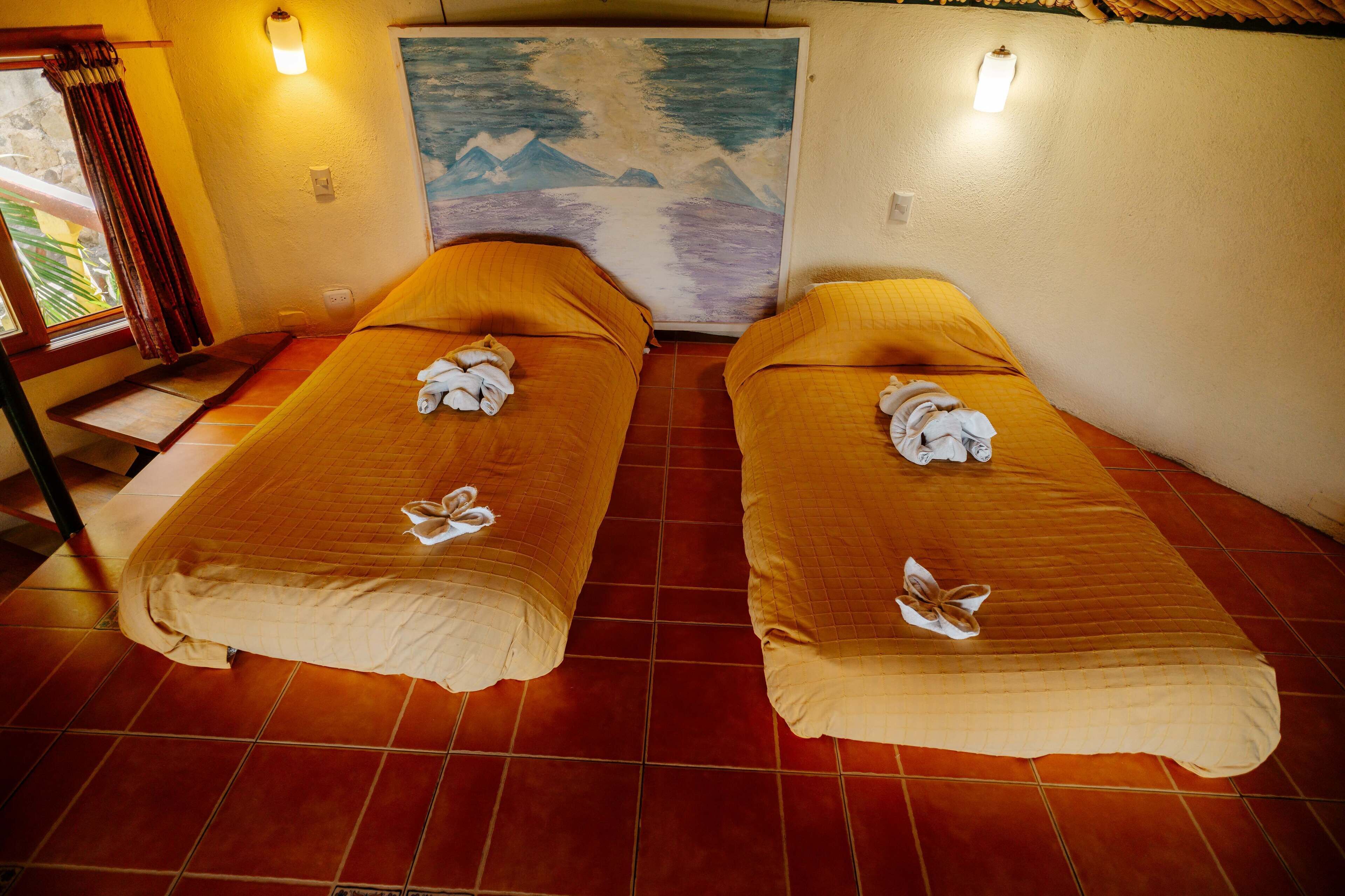 Une chambre avec deux lits, chacun étant équipé d’une serviette et d’un oreiller.