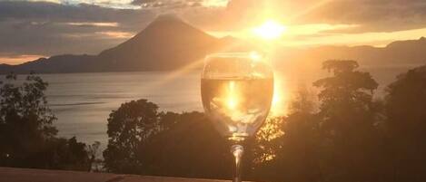 Un vaso de agua sobre un saliente, con un atardecer y montañas al fondo.