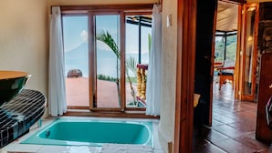 A room with a large sliding glass door leading to an outdoor area, a bathtub, and a dining table.