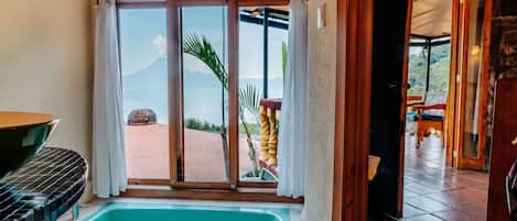 Habitación con un amplio ventanal corredero que da a un área exterior, una bañera y una mesa de comedor.