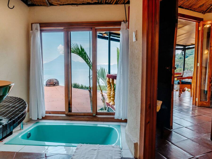 A room with a large sliding glass door leading to an outdoor area, a bathtub, and a dining table.
