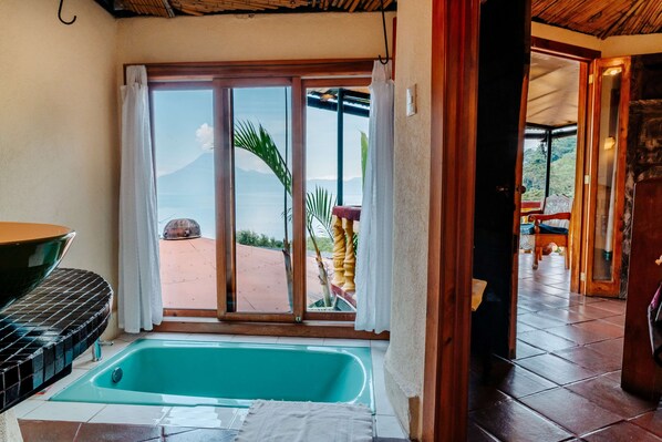 Habitación con un amplio ventanal corredero que da a un área exterior, una bañera y una mesa de comedor.