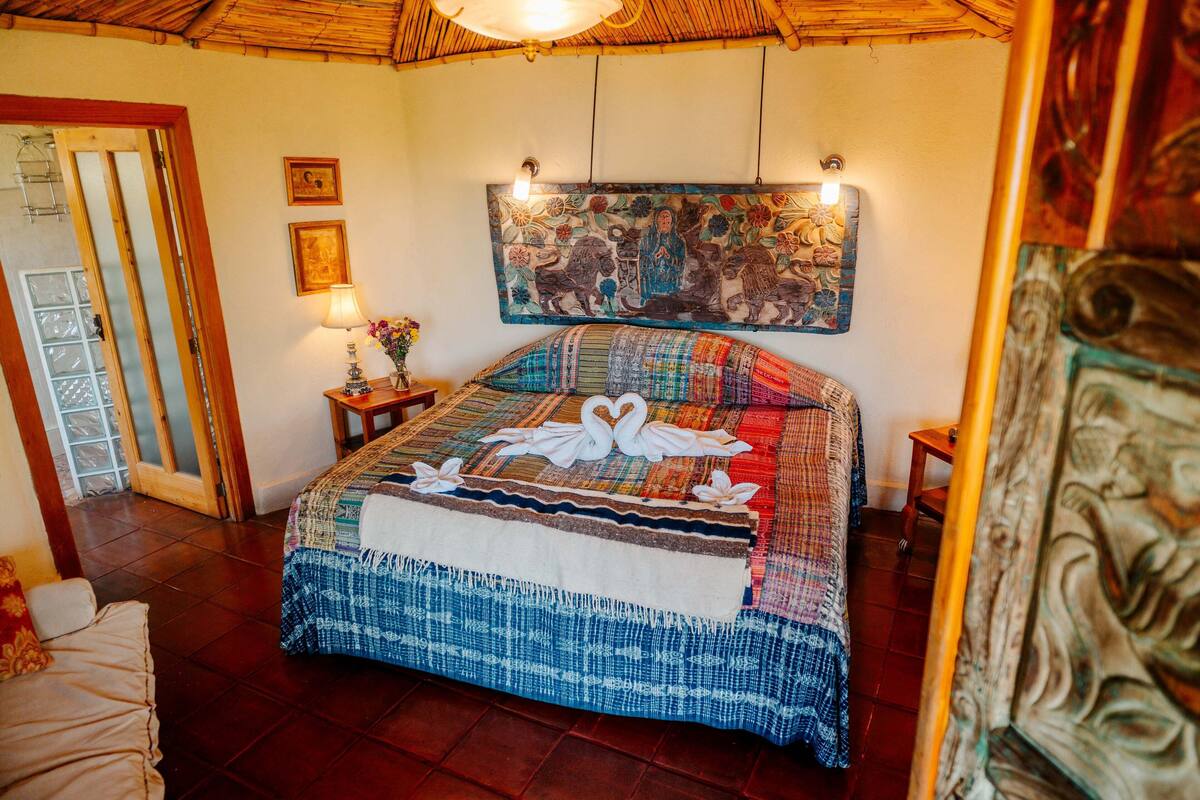 A bed with a colorful quilt and a wall hanging above it.