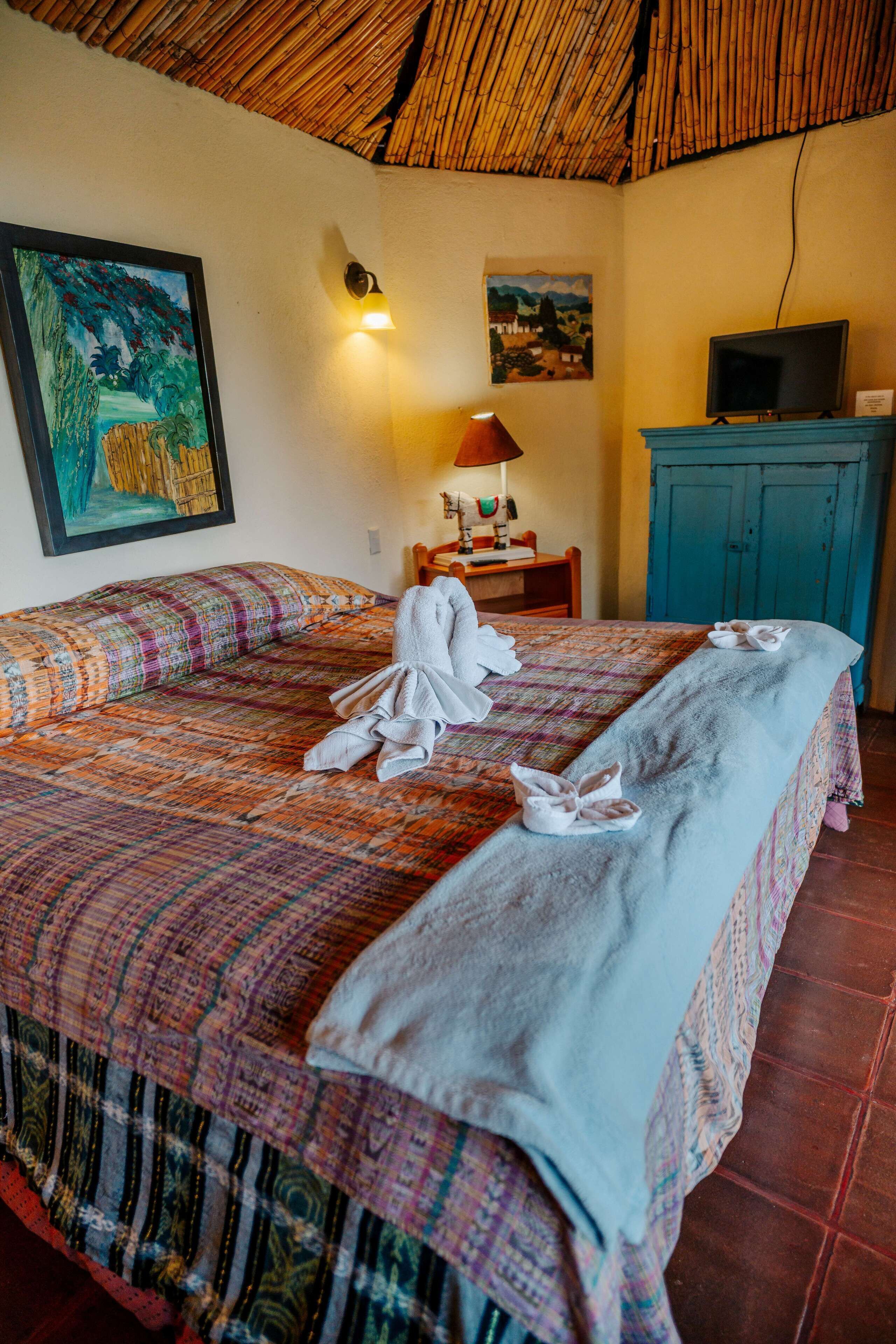 Habitación de hotel con cama, escritorio, televisor y obras de arte en las paredes.