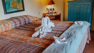 Habitación de hotel con cama, escritorio, televisor y obras de arte en las paredes.