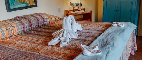 Habitación de hotel con cama, escritorio, televisor y obras de arte en las paredes.