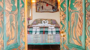 A room with a bed, a hanging light fixture, and a wall tapestry.