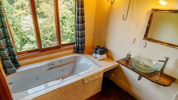 Ein Badezimmer mit Badewanne, Waschbecken aus Glas und einem fenster mit Vorhängen.