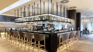 Zona de bar moderna con una isla central, taburetes y una vitrina de cristal.