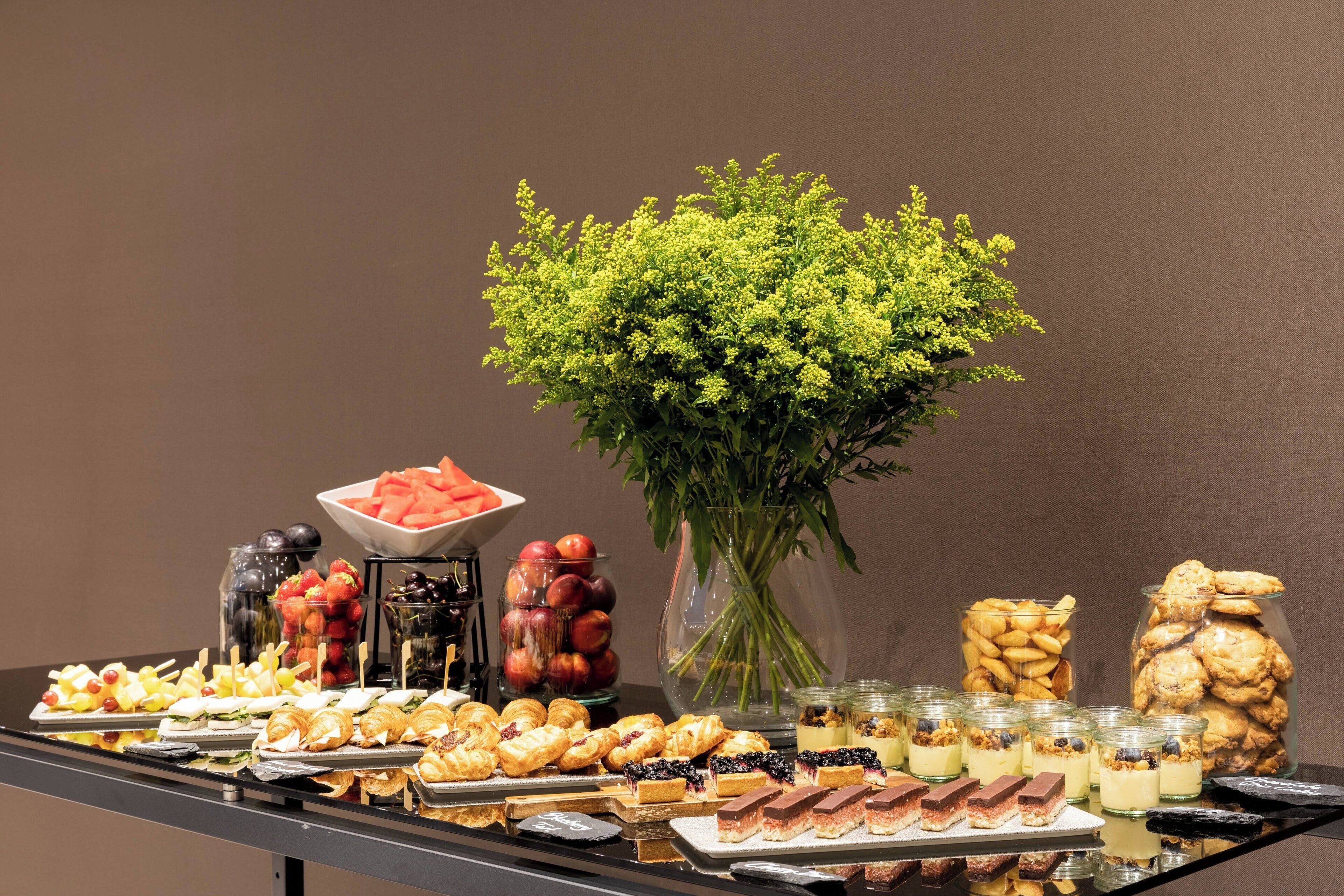 Une table de buffet garnie de divers plats et un vase rempli de fleurs.