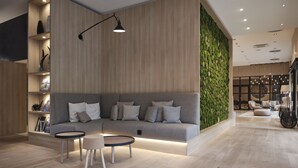 Una sala moderna con un sofá gris, una mesa de centro redonda y una pared vertical con jardín.