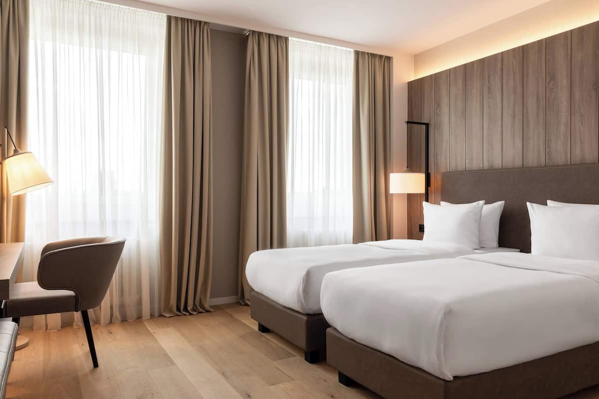 Habitación de hotel con dos camas, un escritorio y una silla.