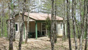 A rustic cabin with a porch, surrounded by trees in a forest. - Ferme-Auberge des Trouilles (Lafrancaise)