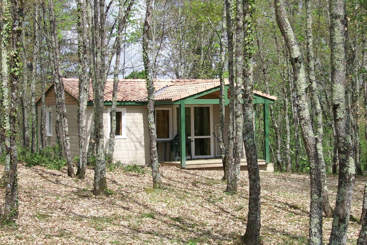 Une petite cabane avec un toit en tuiles, entourée d’arbres.