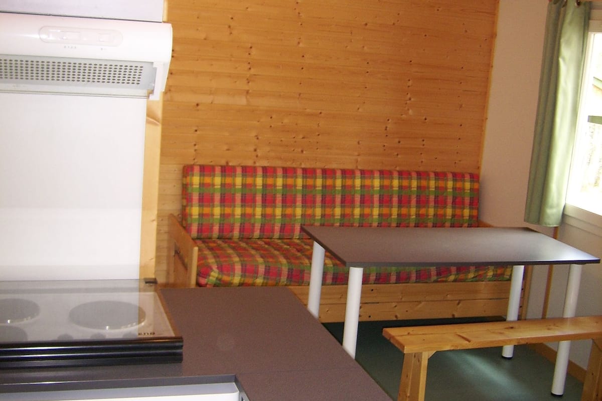 Une cuisine compacte équipée d’une cuisinière, d’un banc et d’une petite table.