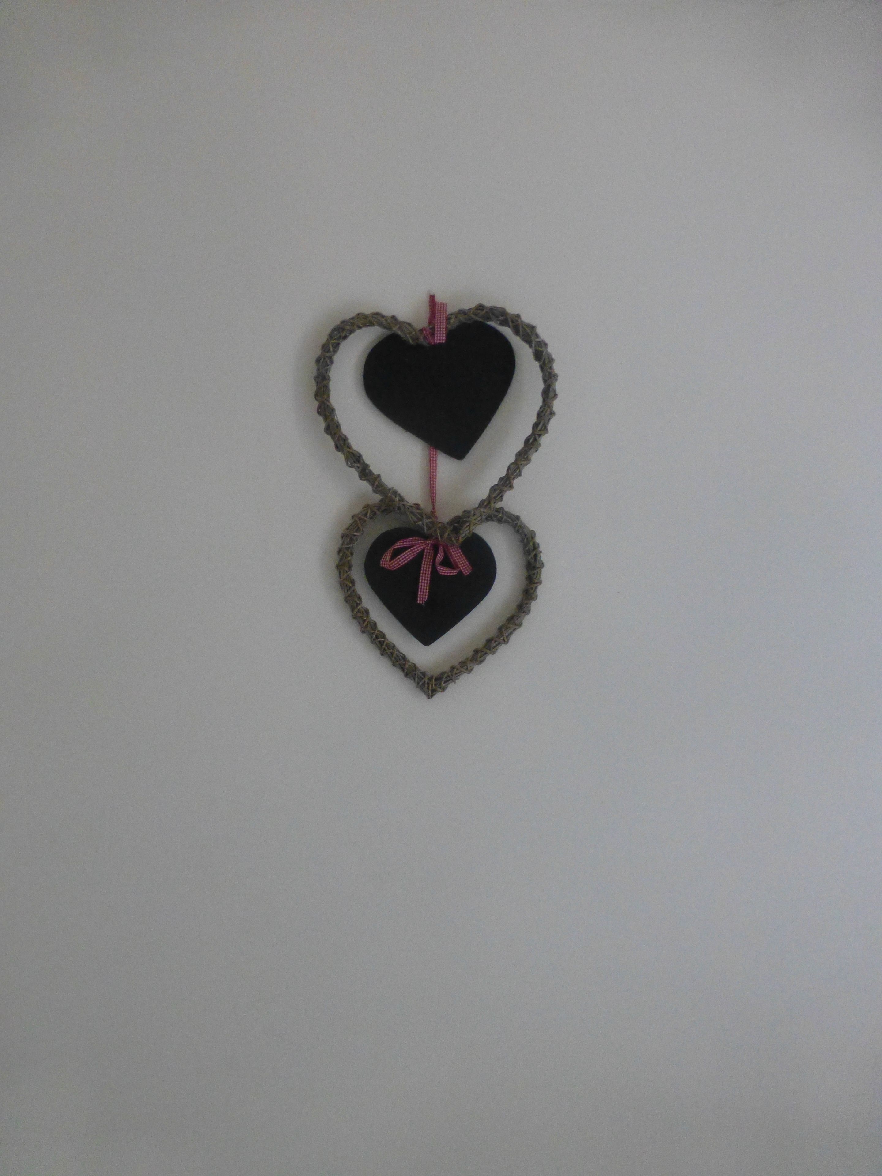 A wall-mounted decoration of two heart shapes, one larger than the other, connected by a string.
