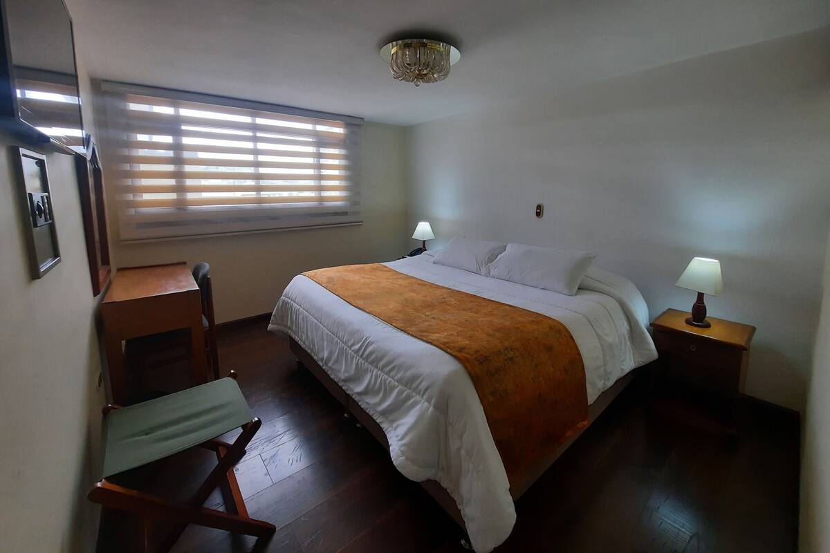 A bedroom with a bed, bedside tables, a desk, and a chair.