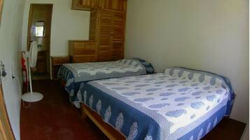 Un dormitorio con dos camas, un armario de madera y un escritorio pequeño con una silla.