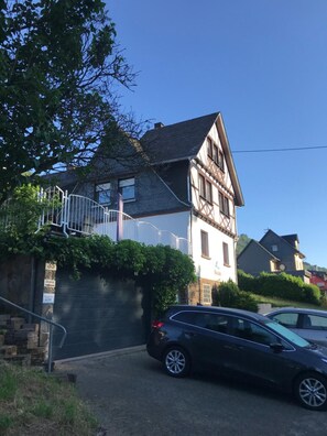 Et toetagers hus med et stejlt tag, en tydelig trappe op til øvre plan og en bil parkeret i indkørslen.
