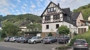 Ein traditionelles Fachwerkhäuschen mit der Beschriftung 'Hotel Rosina' und einem Parkplatz mit mehreren Autos.