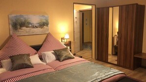 Ein Schlafzimmer mit einem Bett, Kissen, einem Nachttisch, einer Lampe, einem Gemälde und einem Kleiderschrank.