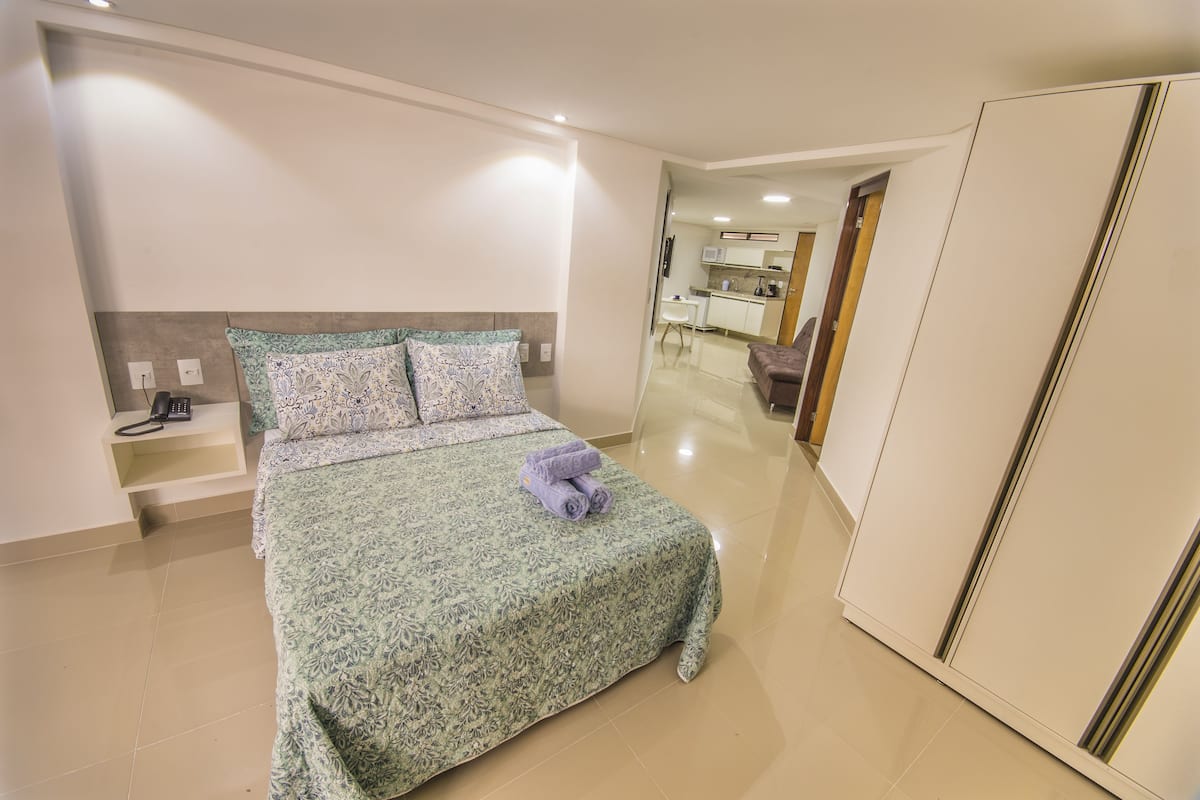A bedroom with a bed, bedside table, and a wardrobe.