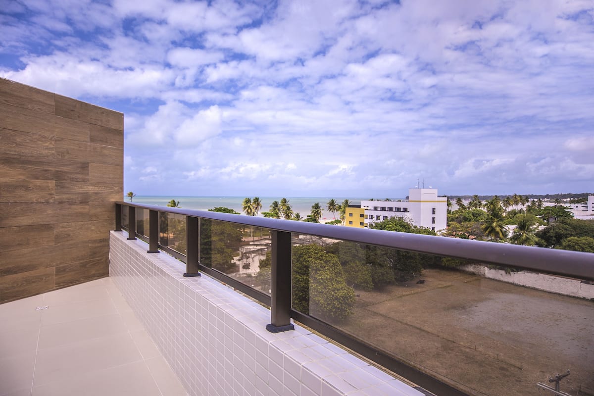 A balcony with a view of the beach and palm trees.
