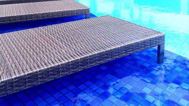 A swimming pool with blue tiles and wicker lounge chairs. - GOLDFLAT Cabo Branco by Penareia.tur.br (João Pessoa)
