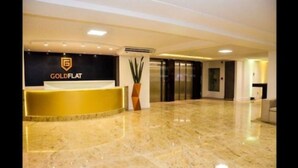 A reception area with a GoldFlat sign, a potted plant, and a marble floor. - GOLDFLAT Cabo Branco by Penareia.tur.br (João Pessoa)