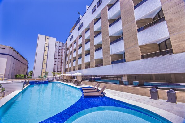 Un hôtel doté d’une piscine, d’un espace extérieur aménagé et d’une façade moderne.