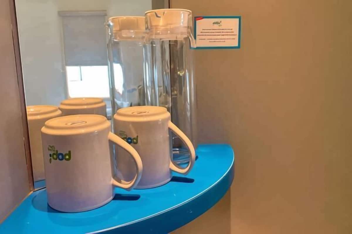 A blue counter with three white mugs and a glass pitcher on it.