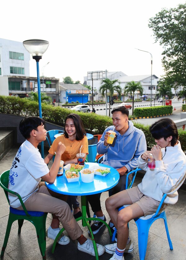 Four people seated at a round table outdoors with a cityscape in the background.