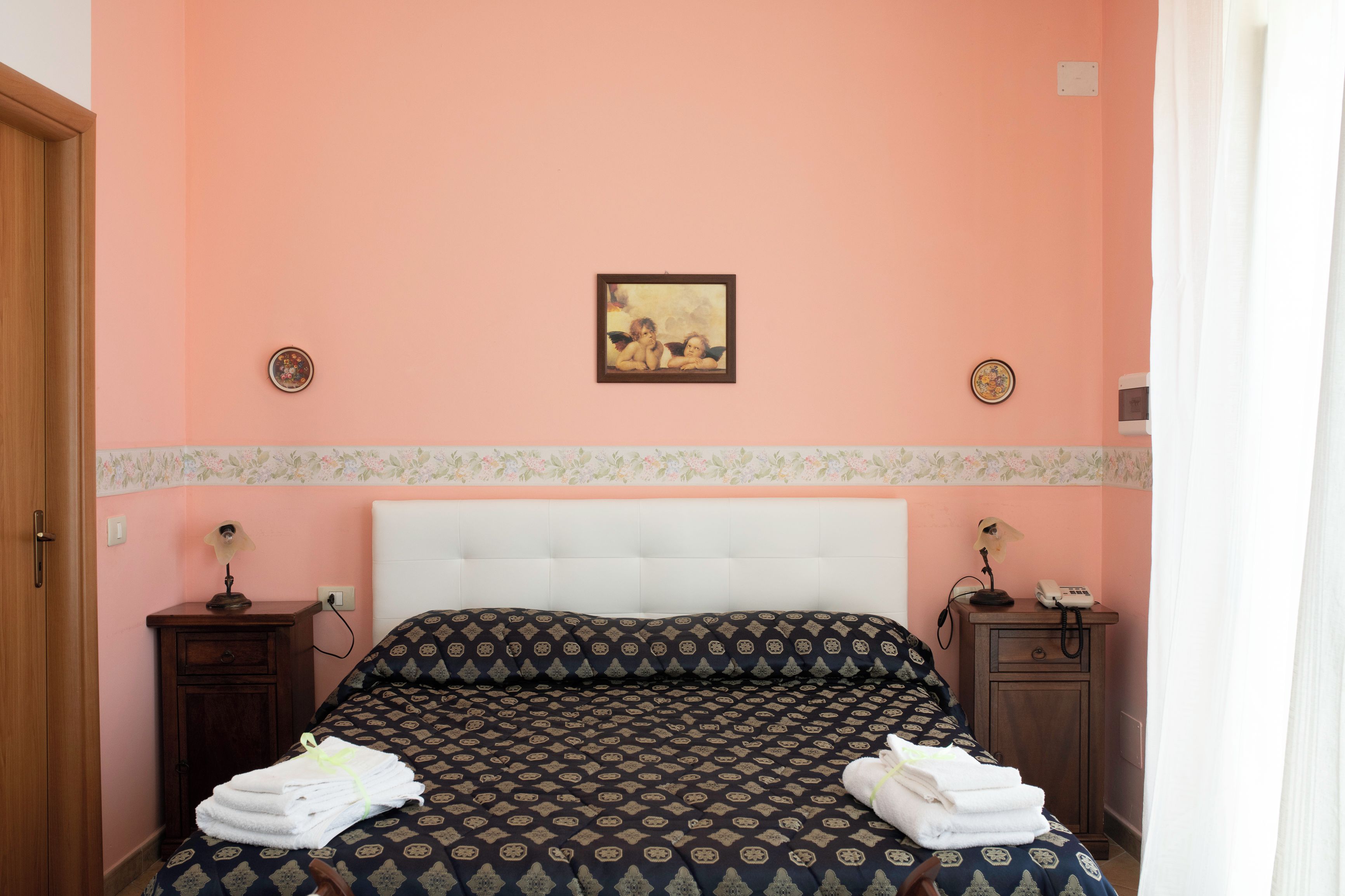 A bedroom with a bed, two nightstands, a painting on the wall, and a door.