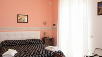 Un dormitorio con una colcha estampada, una mesita de noche con una lámpara y un cuadro en la pared.