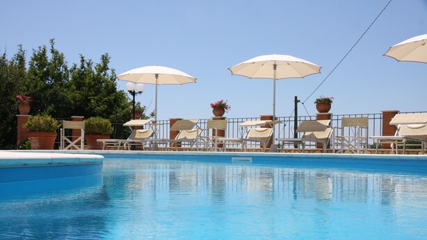 Une piscine avec des chaises longues et des parasols.