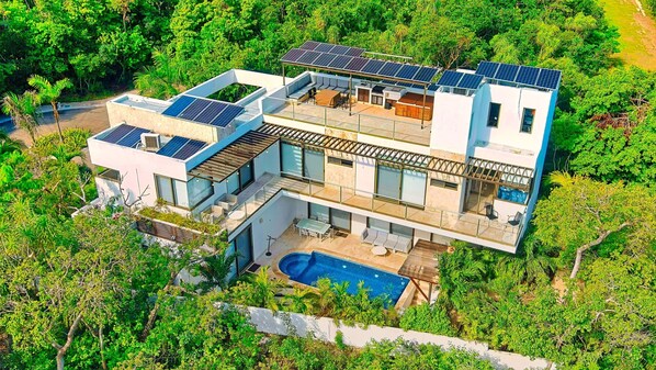 Ein modernes, zweistöckiges Haus mit Pool, Solaranlage und üppigem Garten.
