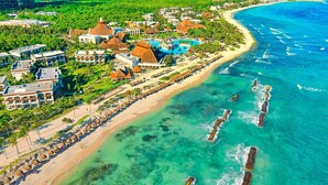 An aerial view of a resort with a beach, a large pool, and thatched-roof buildings. - Luxury Home Riviera Maya Bahia Principe 5 Star Resort Pool Jacuzzis Beach Access (Akumal)