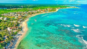 Luftaufnahme eines Küstenresorts mit Strandhäusern, klarem türkisblauem Wasser und einer Marina.