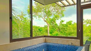 A corner bathroom with a blue mosaic bathtub, large windows, and a view of greenery. - Luxury Home Riviera Maya Bahia Principe 5 Star Resort Pool Jacuzzis Beach Access (Akumal)
