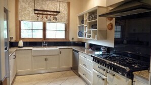 A kitchen with white cabinets, a black stove, and a window with curtains.