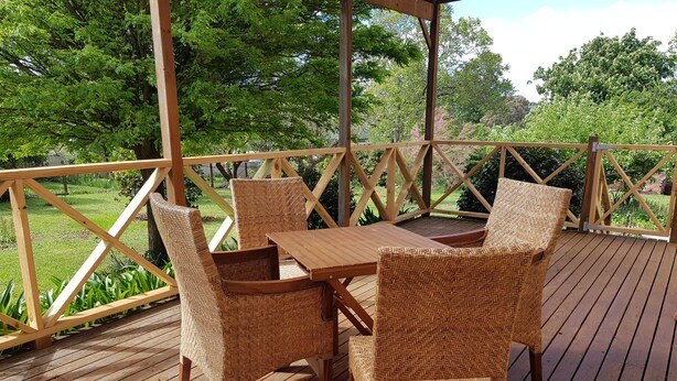 A wooden deck with a table and four wicker chairs.